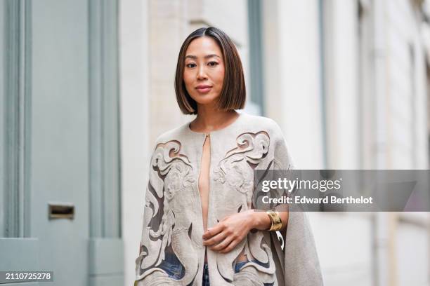 Aimee Song wears a bangle, a beige embroidered cape dress with transparent inlays, outside Valentino , during the Womenswear Fall/Winter 2024/2025 as...