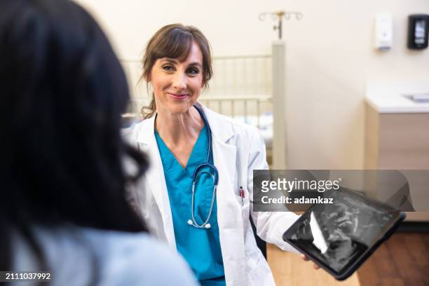doctor and pregnant patient reviewing ultrasound on tablet - 2 5 maanden stockfoto's en -beelden