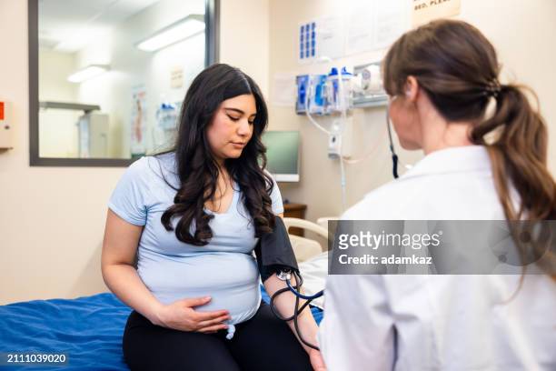 doctor checking a pregnant woman's blood pressure - 2 5 maanden stockfoto's en -beelden