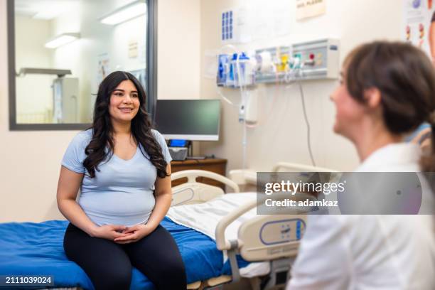pregnant hispanic woman and doctor discussiong pregnancy in a medical exam room - 2 5 maanden stockfoto's en -beelden