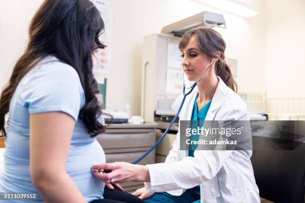 doctor using a stethoscope to listen to a pregnant woman's fetus - 2 5 maanden stockfoto's en -beelden