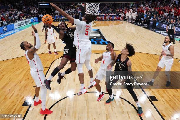 Manny Obaseki of the Texas A&M Aggies attempts to shoot the ball between J'Wan Roberts and Ja'Vier Francis of the Houston Cougars during the second...