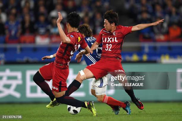 Teruhito Nakagawa of Yokohama F.Marinos is challenged by Koki Anzai and Tomoya Inukai of Kashima Antlers during the J.League J1 match between...