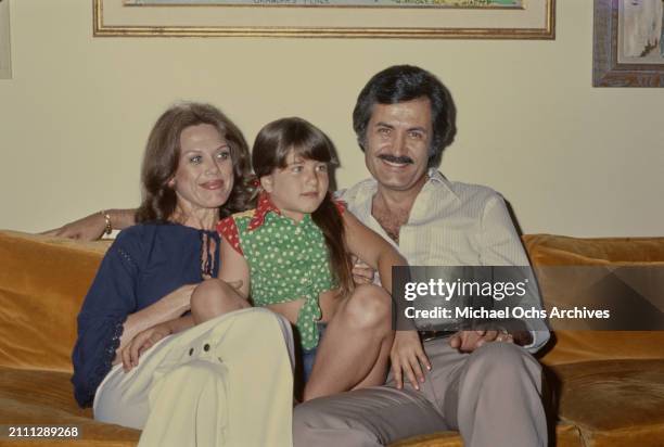 American actress Nancy Dow, wearing a dark blue blouse, sitting on a sofa with her daughter, American actress Jennifer Aniston, wearing a red and...