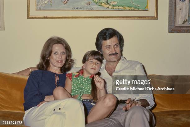 American actress Nancy Dow, wearing a dark blue blouse, sitting on a sofa with her daughter, American actress Jennifer Aniston, wearing a red and...