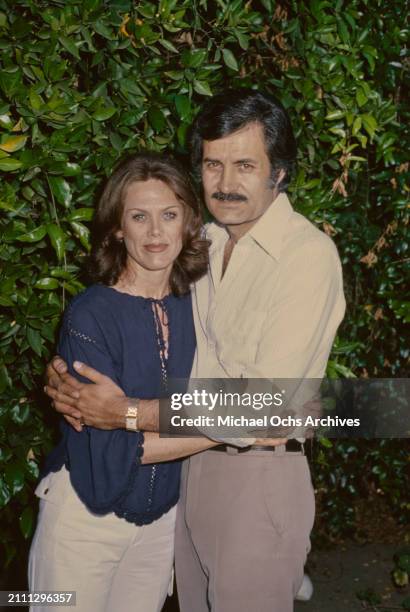 American actress Nancy Dow, wearing a dark blue blouse, embraced by her husband, Greek-born American actor John Aniston, who wears a white shirt,...