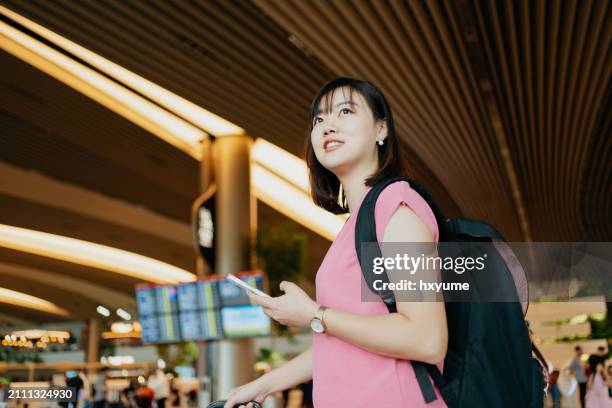 young asian woman using smartphone in the airport - changi airport stock pictures, royalty-free photos & images