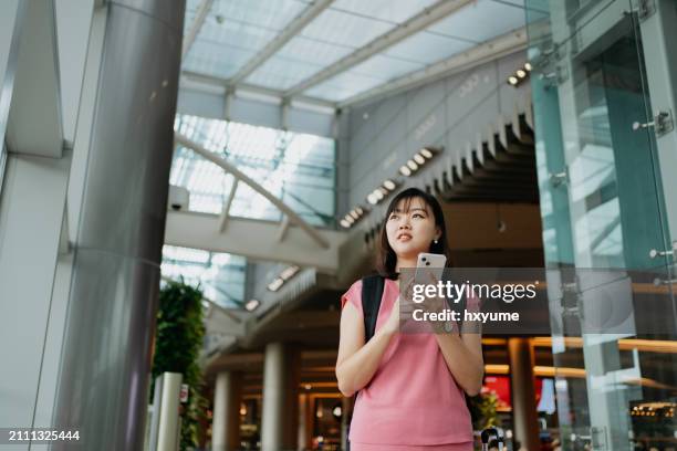 young asian woman using smartphone in the airport - changi airport stock pictures, royalty-free photos & images