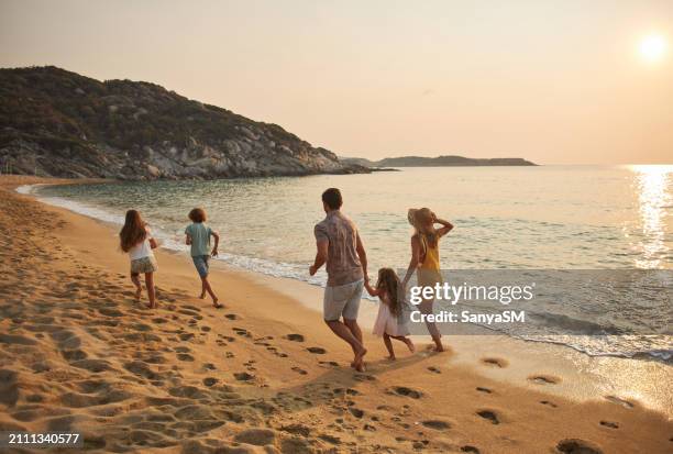 a family run hand in hand down a tropical paradise beach during sunset - vacation stock pictures, royalty-free photos & images