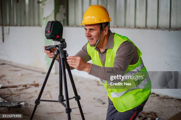 a construction worker uses a laser level - waterpas stockfoto's en -beelden