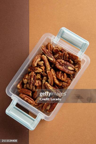 pecans in plastic on a colourful background - pecans isolated stock pictures, royalty-free photos & images