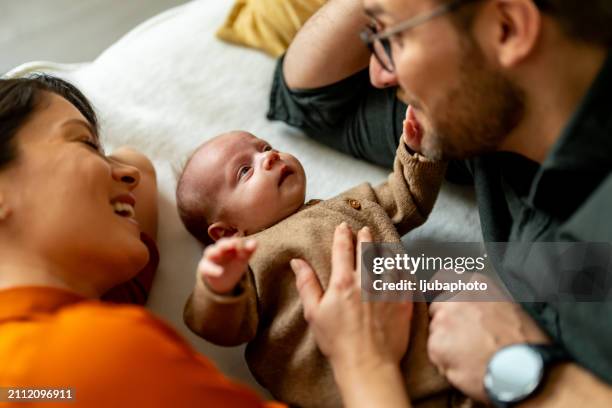 couple enjoying time at home with adopted baby - adoption stock pictures, royalty-free photos & images