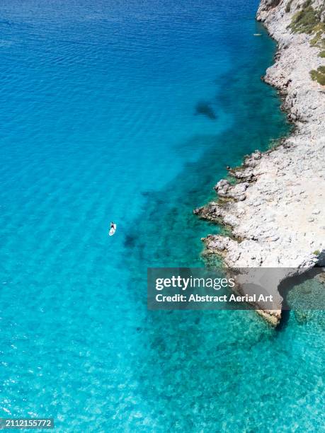 paddleboarder next to the coastline shot from a high angle perspective , crete, greece - península fotografías e imágenes de stock