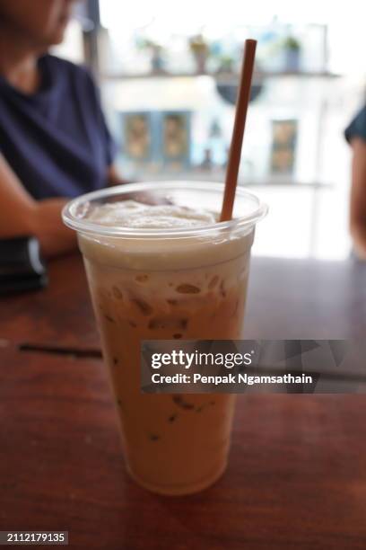 close up view of ice cubes in cold brewed coffee cappuccino in plastic cup put on wooden desk blurred background, drink beverage - sugary coffee drink stock pictures, royalty-free photos & images