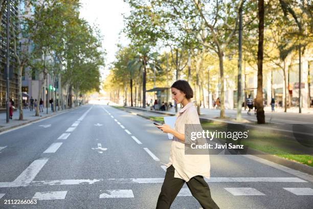 busy businesswoman walking and using smartphone on city street - crossing imagens e fotografias de stock