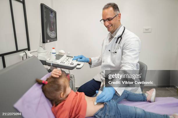 männlicher kinderarzt untersucht kleines mädchen mit ultraschall in der medizinischen klinik - male stomach stock-fotos und bilder