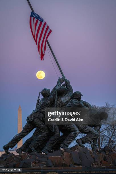 The full Worm Moon rises behind the US Marine Corps War Memorial with the Washington Monument in the background on March 24 in Arlington, VA.