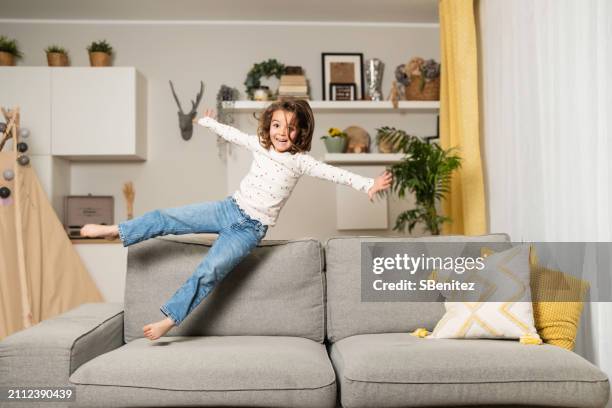 young girl jumping on the couch - extreem weer stock pictures, royalty-free photos & images