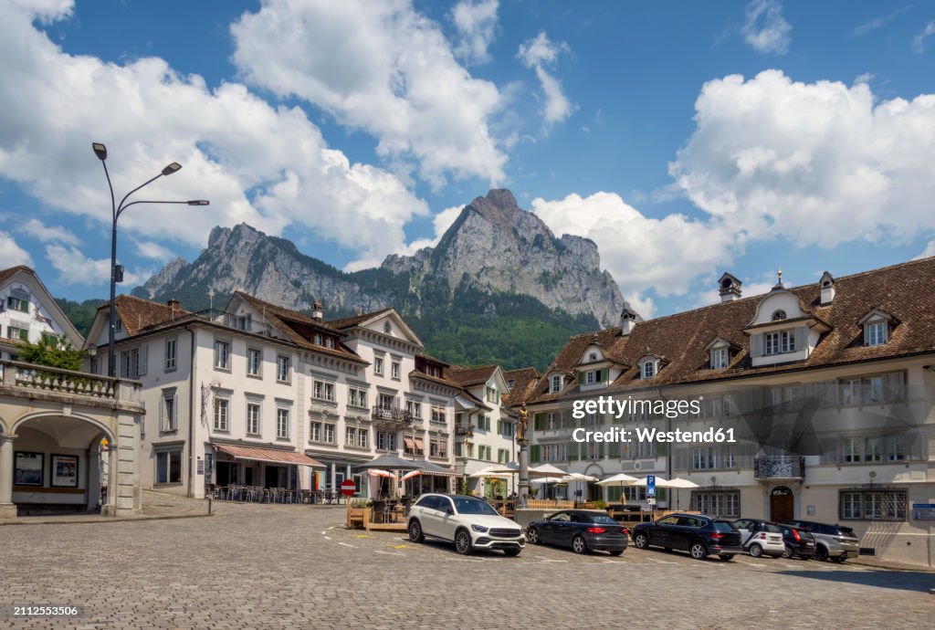 Vehicles parked near Main Square with summit of Grosser Mythen under sky in Central Switzerland, Canton Schwyz, Switzerland