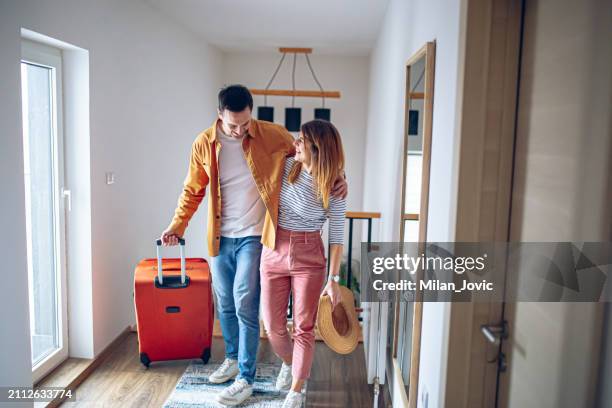 pareja joven caminando por el pasillo mientras tira de su maleta - motel pareja fotografías e imágenes de stock