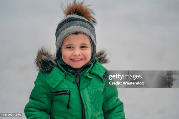 smiling boy wearing warm clothes in winter - parka coat stock pictures, royalty-free photos & images