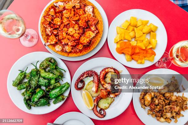 dinner with octopus dishes and padron peppers at spanish restaurant, high angle view - tapas stock pictures, royalty-free photos & images
