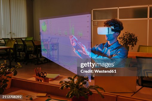 Businessman interacting with graphical interface using virtual reality simulator in office Businessman interacting with graphical interface using virtual reality simulator in office