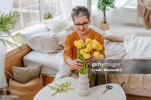woman putting tulips in vase at home - arranging tulips stock pictures, royalty-free photos & images