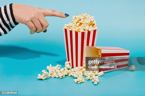 hand of woman touching popcorn in red striped container - blue nail polish stock pictures, royalty-free photos & images