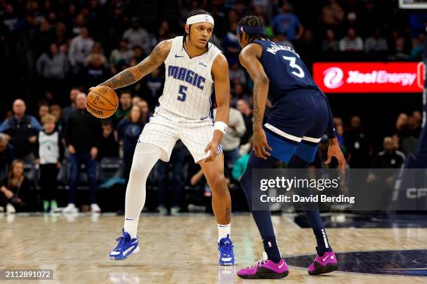 Paolo Banchero of the Orlando Magic dribbles the ball against Jaden McDaniels of the Minnesota Timberwolves in the fourth quarter at Target Center on...