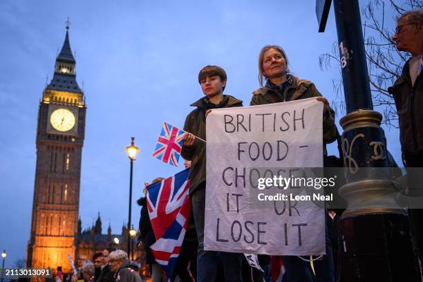 Woman holds up a banner as farmers drive tractors and agricultural vehicles through Parliament Square during a protest over the increased pressures...