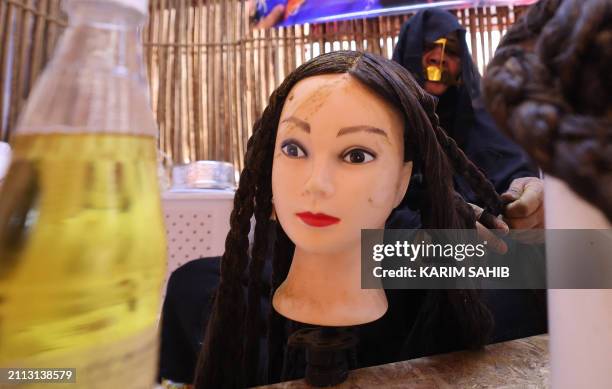 An Emirati woman applies henna dye to a mannequin's hair at the annual traditional crafts and industries heritage festival in Qattara market in the...