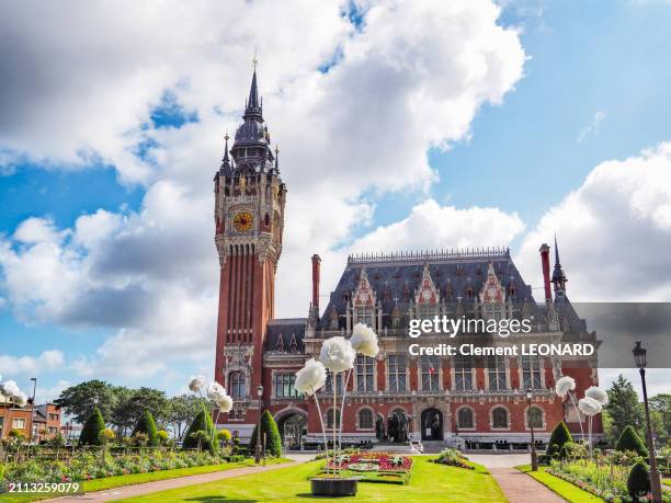 the hôtel de ville de calais (calais town hall) and its belfry (clock tower) on the square of the unknown soldier, decorated with flowerbeds and giant fake flowers, unesco world heritage site - pas-de-calais - nord-pas-de-calais - northern france. - calais monument foto e immagini stock