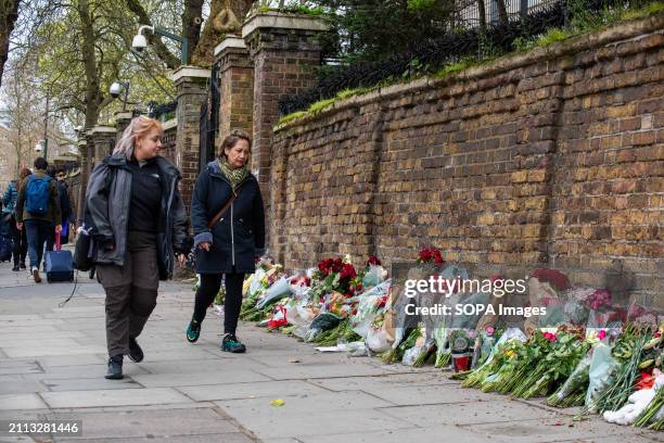 Pedestrians look at the flowers outside the Russian Embassy in London as they walk by. Russian diasporas are mourning in London, UK because of the...