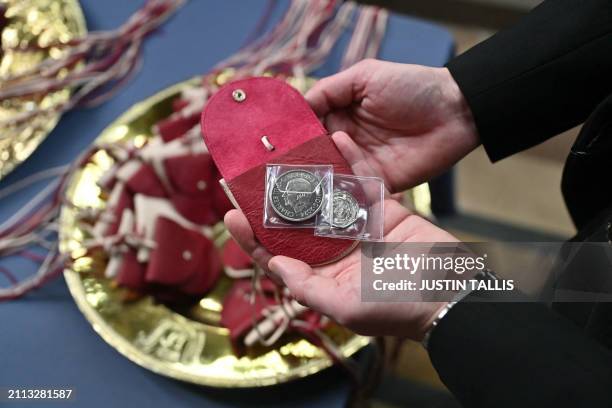 The red purses contains a £5 coin which features the image of a Tudor Dragon, and a 50p coin commemorating the RNLI as Britain's Queen Camilla...