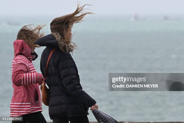 Women walk in the wind on the seaside, as Meteo France has issued an orange warning for wind in several departments, in Saint-Malo, western France on...