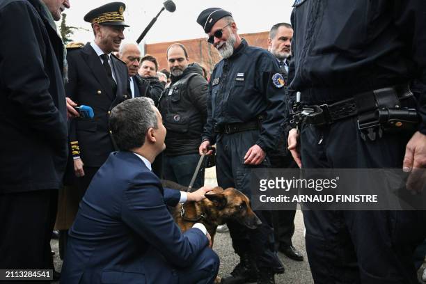 French Minister for Interior and Overseas Gerald Darmanin pets a police dog as he speaks with French police officers involved in the newly launched...