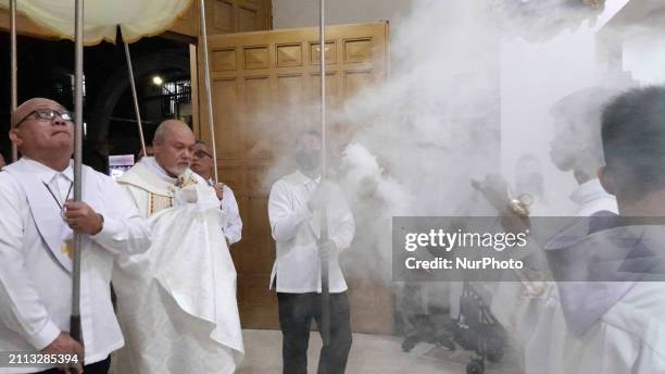 Father Bernardo Lanuza, OFM, is holding the wrapped consecrated Eucharist hosts while an altar server is smoking religious incense for the procession...