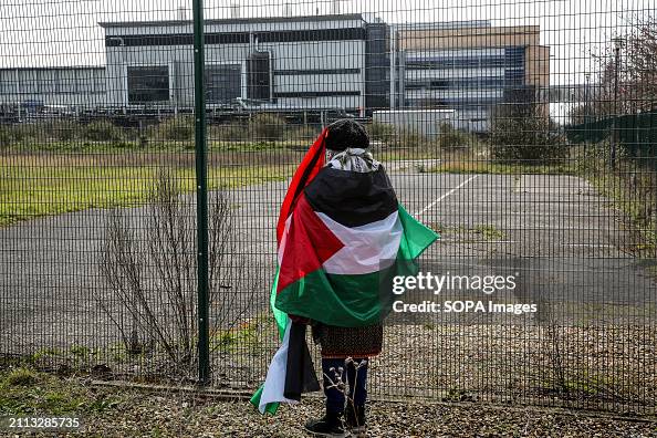 A supporter of the activists gazes through the fence towards...