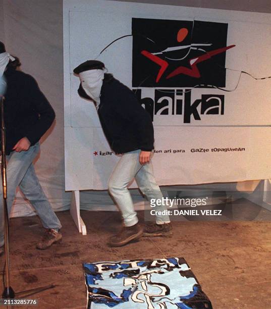 Deux jeunes gens masqués quittent l'estrade après avoir fait applaudir le drapeau de l'ETA qu'ils ont posé à terre le 22 avril 2000 à Cambo-les-Bains...