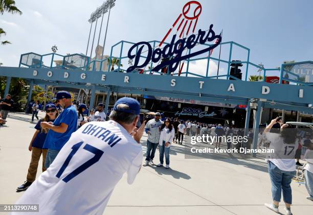 Fans take photographs near the Jackie Robinson statue before the start of the Opening Day baseball game between the Los Angeles Dodgers and St. Louis...