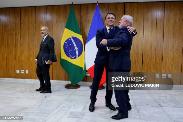Brazil's President Luiz Inacio Lula da Silva and France's President Emmanuel Macron hug each other after a bilateral agreement signing ceremony at...