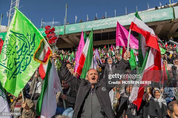 Iranian people wave Iranian and Palestinian flags during a rally in solidarity with Palestinians in Azadi Stadium in Tehran, Iran on March 26, 2024....