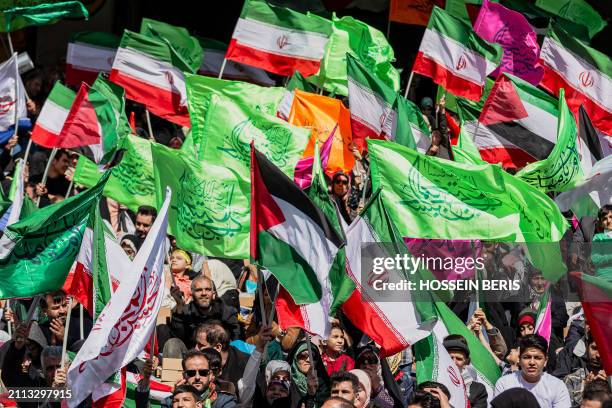 Iranian people wave Iranian and Palestinian flags during a rally in solidarity with Palestinians in Azadi Stadium in Tehran, Iran on March 26, 2024....