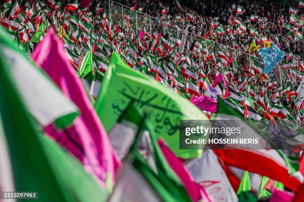 Iranian people wave Iranian and Palestinian flags during a rally in solidarity with Palestinians in Azadi Stadium in Tehran, Iran on March 26, 2024....