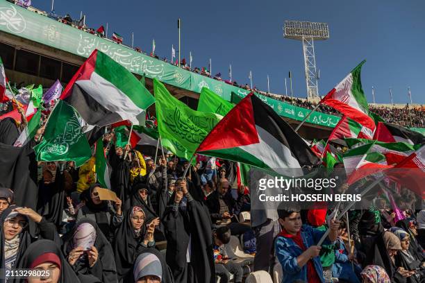 Iranian people wave Iranian and Palestinian flags during a rally in solidarity with Palestinians in Azadi Stadium in Tehran, Iran on March 26, 2024....