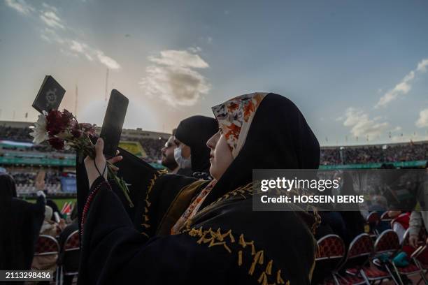An Iranian veiled woman takes a picture of a Quran in her hand during a rally in solidarity with Palestinians in Azadi Stadium in Tehran, Iran on...