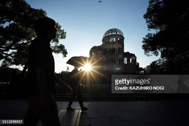 This photo taken on August 5, 2023 shows pedestrians walking past the Atomic Bomb Dome beside the Hiroshima Peace Memorial Park in Hiroshima, ahead...