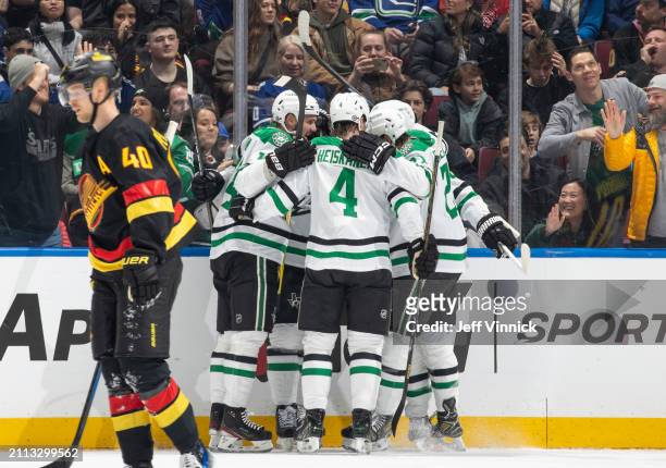 Roope Hintz of the Dallas Stars celebrates his goal with teammates as Elias Pettersson of the Vancouver Canucks skates on dejected during the first...