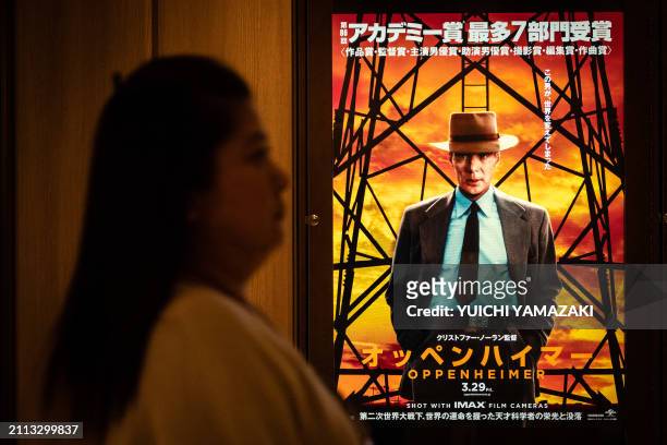 Woman walks past a poster for the film 'Oppenheimer' in Tokyo on March 29, 2024. Oscars best picture winner "Oppenheimer" was finally released on...